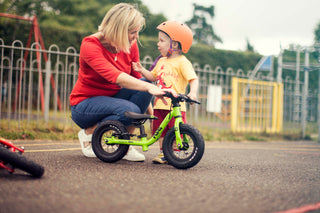 child with a green balance bike 