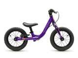 A purple Academy balance bike with black tires, saddle, and handlebars, shown from a side profile on a white background.