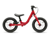 A red balance bike with black tires, a black saddle, and black handlebars, shown from a side profile on a white background. The brand name 'ACADEMY' is printed vertically on the frame.